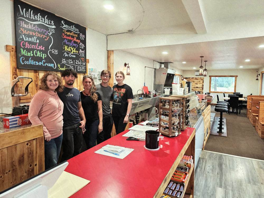 Five members of the Elmira Store crew standing behind the red counter beneath the hand-lettered milkshake and smoothie chalkboard.
